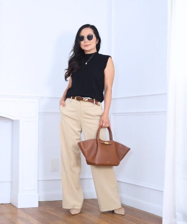 Stylish outfit in black sleeveless top and beige pants with sunglasses and brown handbag.